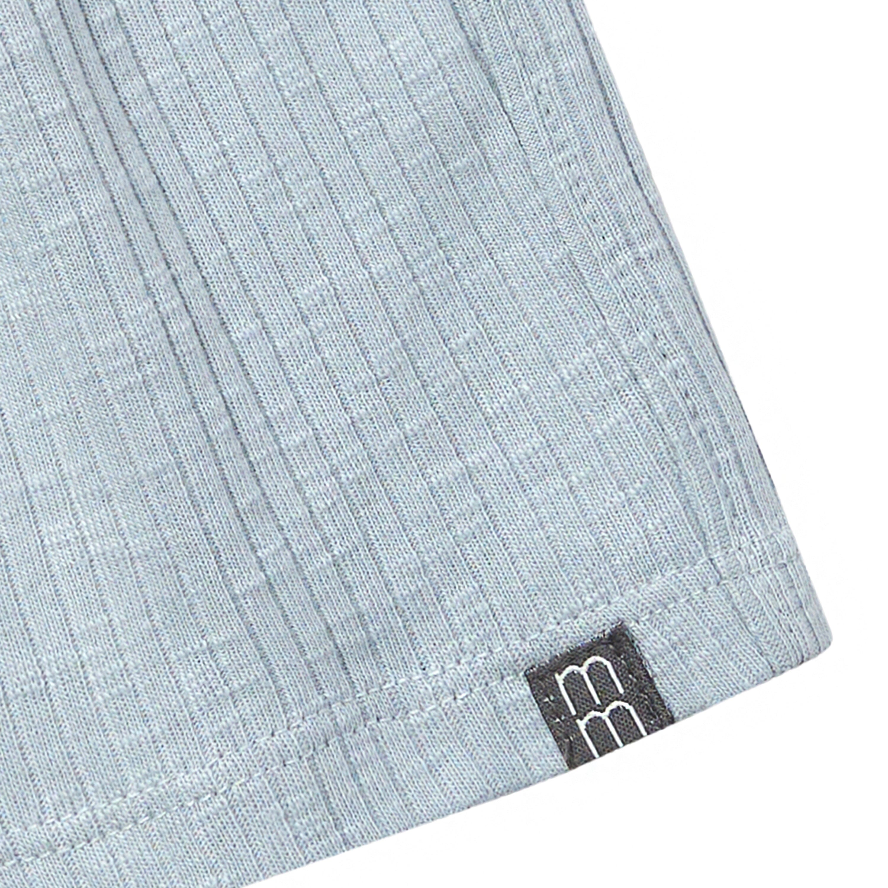 Close-up of light blue fabric with a brand logo on a white background