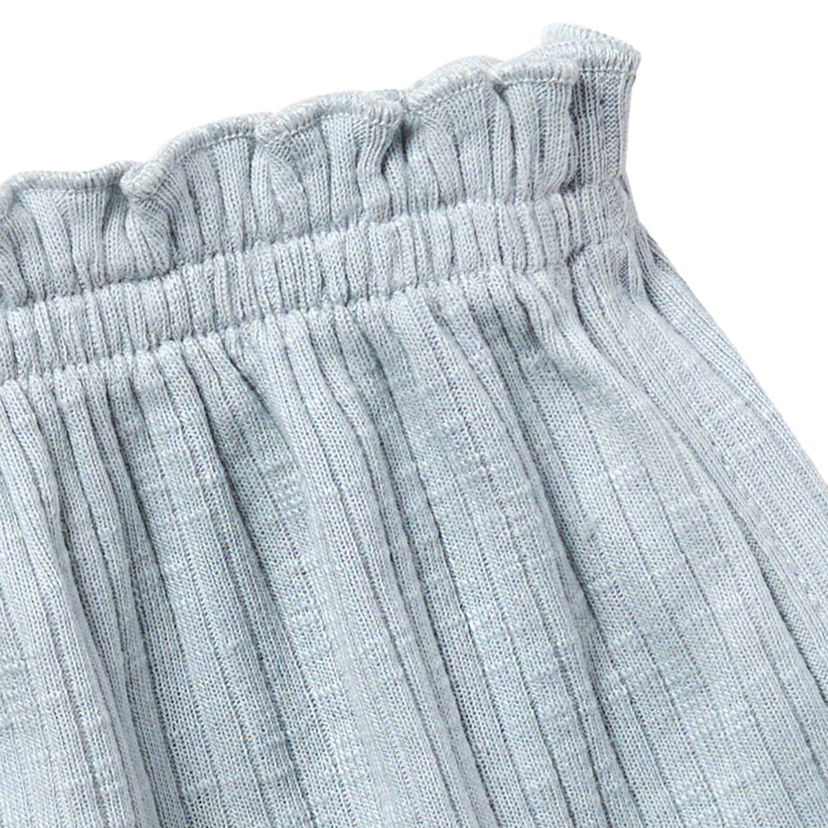 Close-up of light blue textured fabric with an elastic waistband on a white background