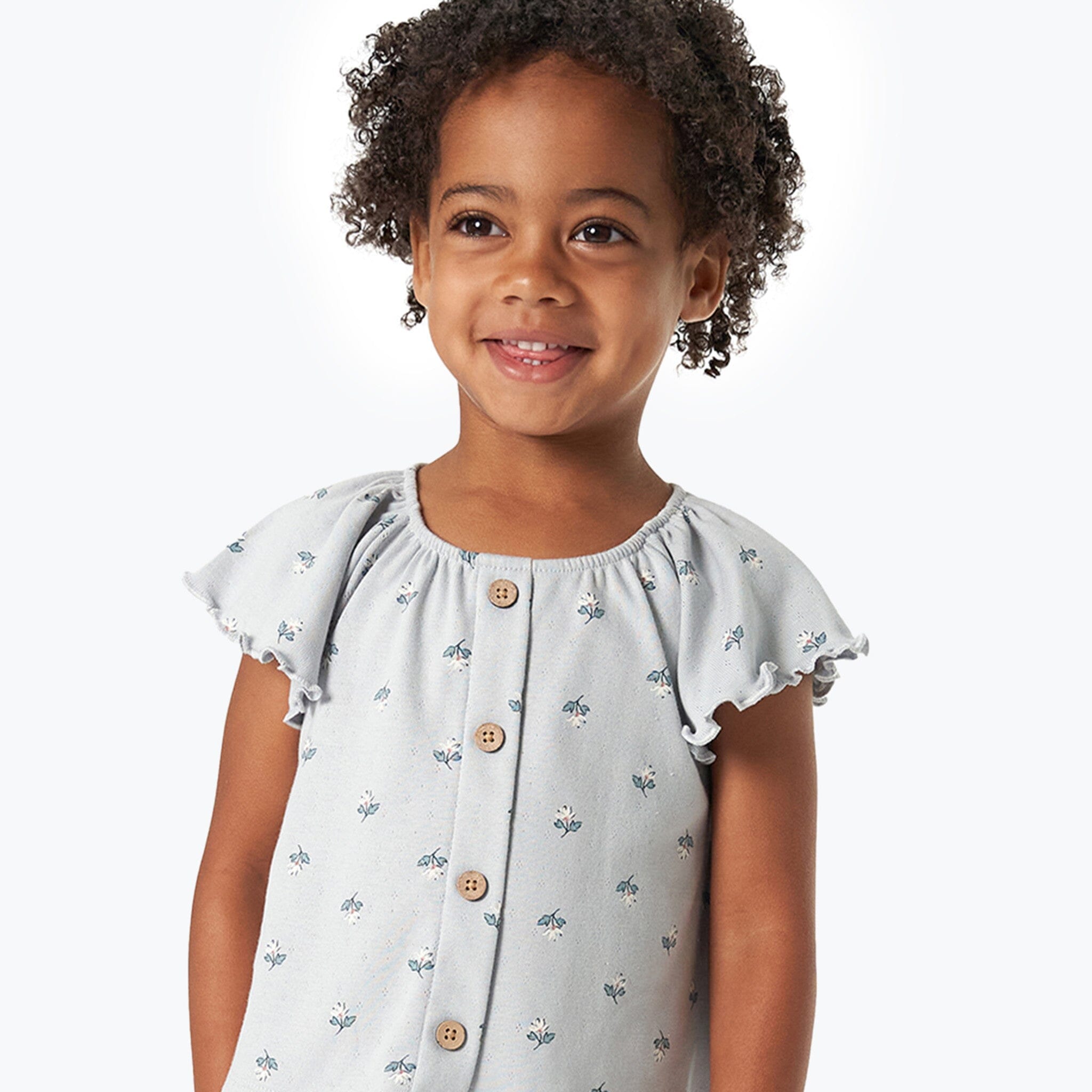 Young girl wearing a light blue dress with floral patterns on a white background