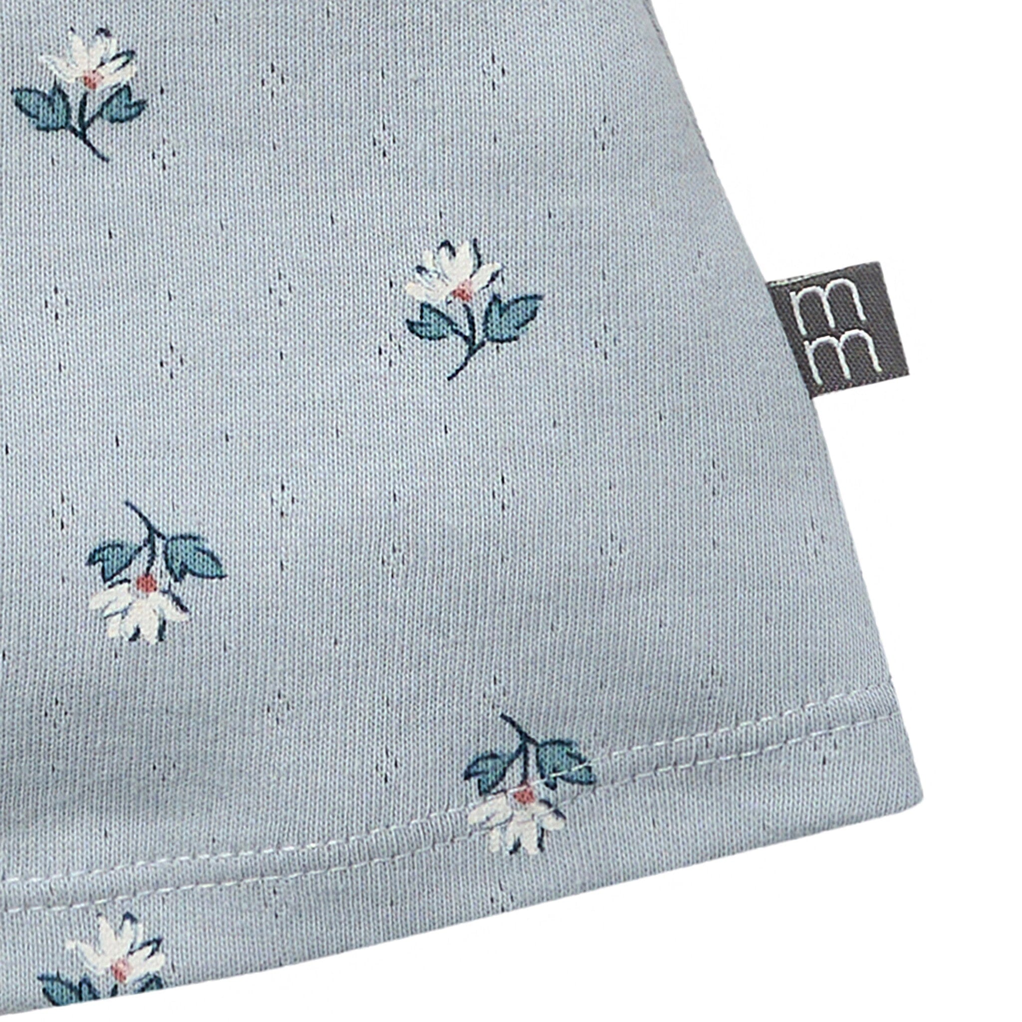 Light blue fabric with floral pattern and a brand tag on a white background