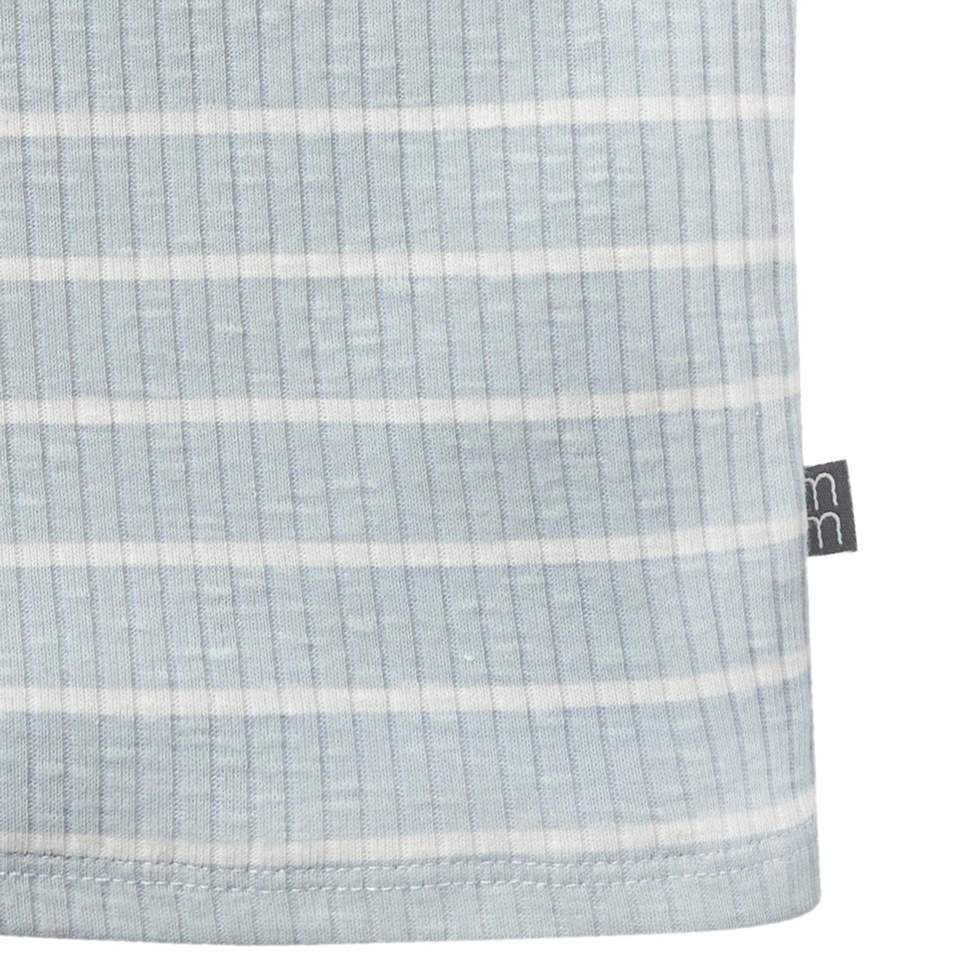 Close-up of a light blue fabric with white stripes and a brand tag on a white background