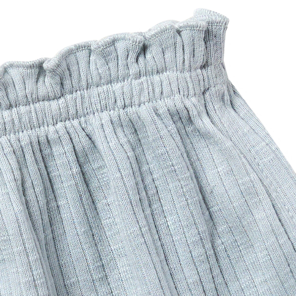 Close-up of light gray textured pants with an elastic waistband on a white background