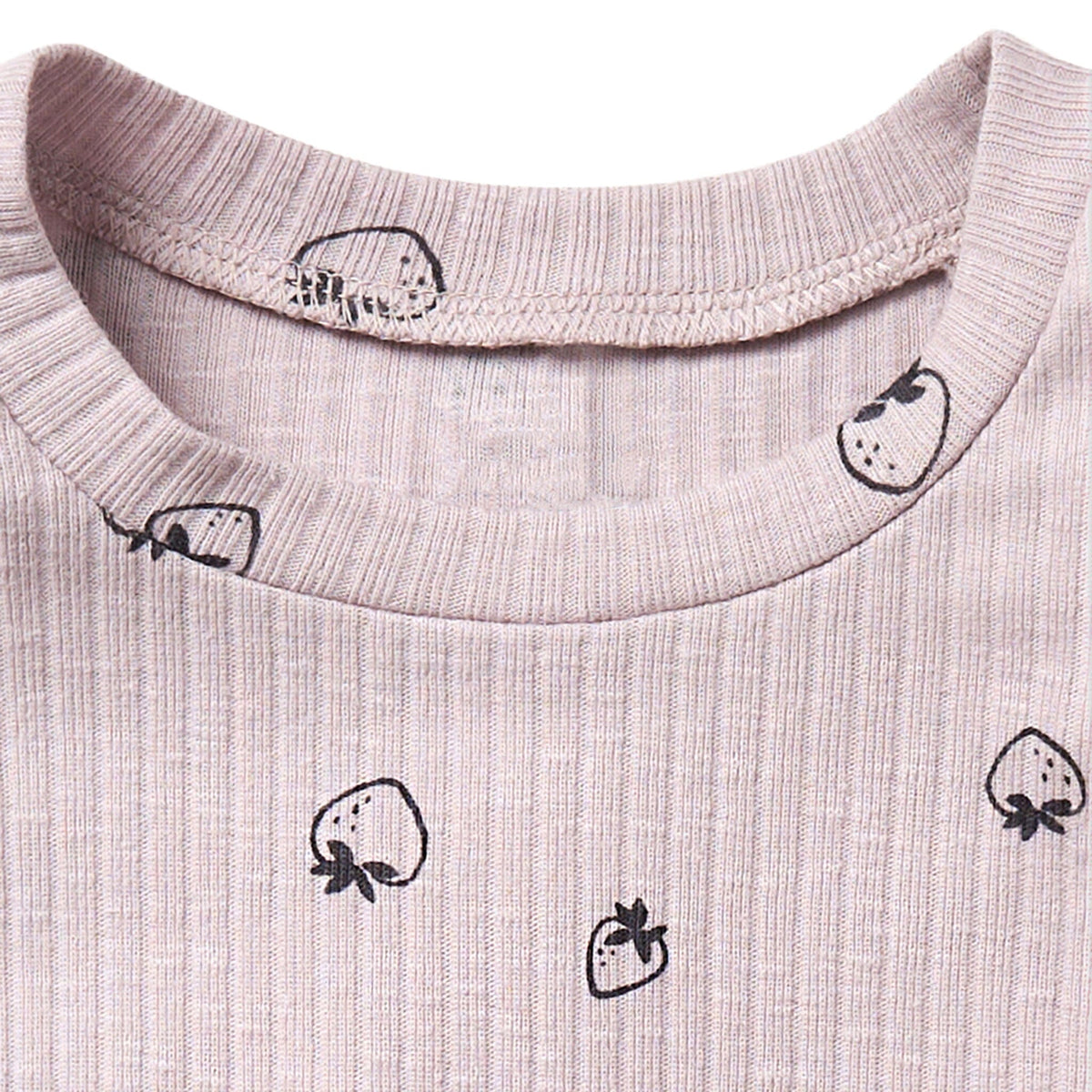 Close-up of a light pink fabric with black strawberry prints on a white background