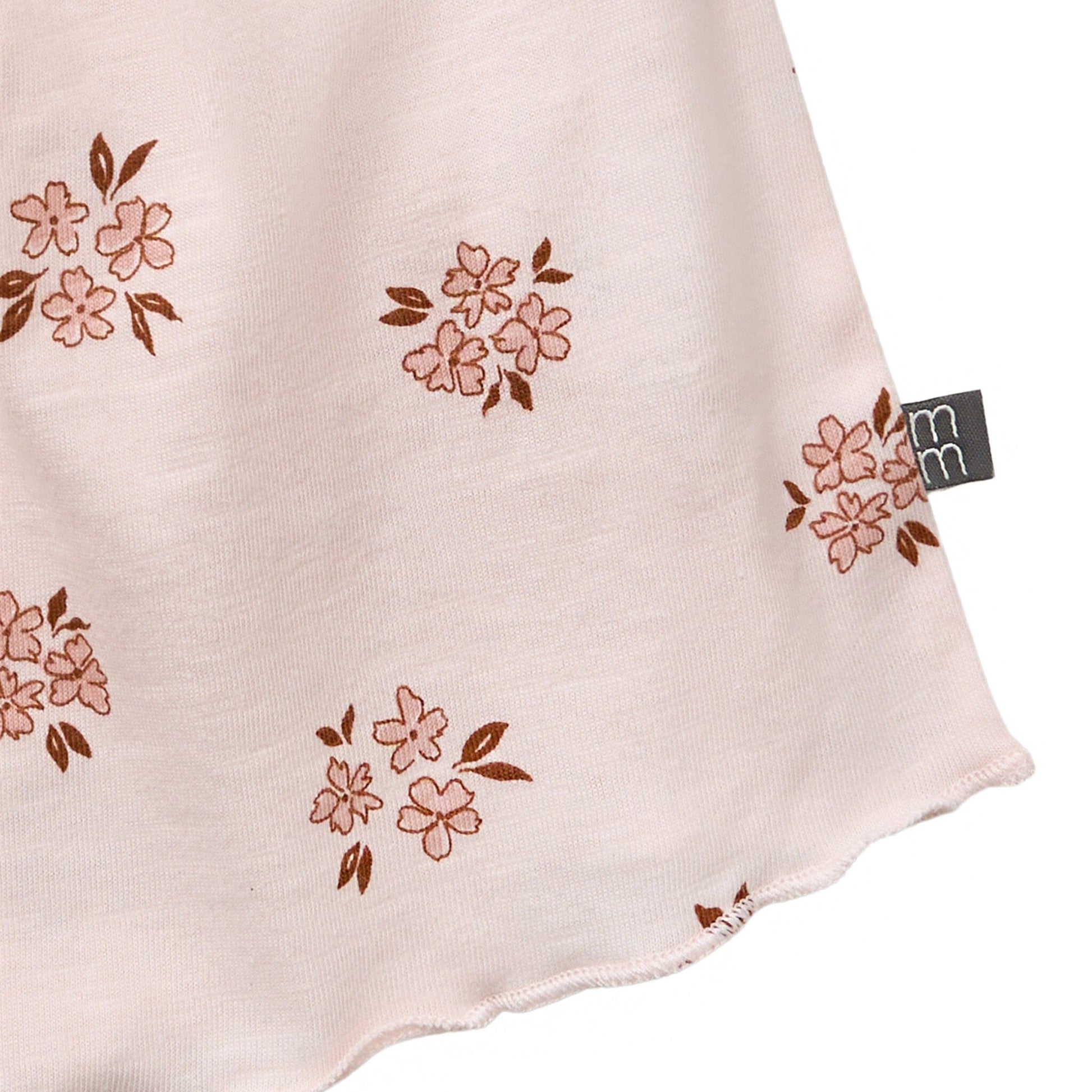 Fabric with floral pattern and a visible brand tag on a beige background