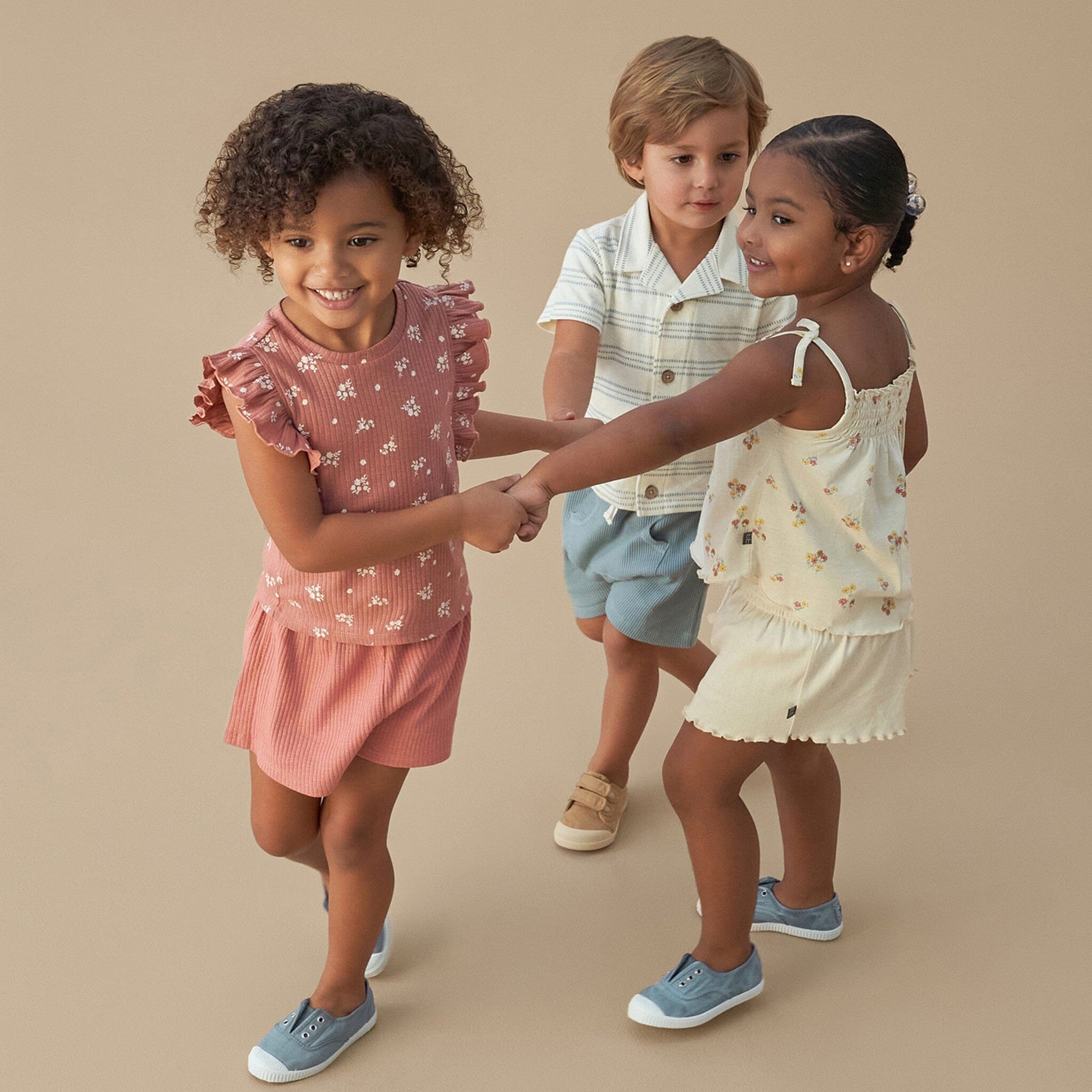 Three children holding hands against a beige background