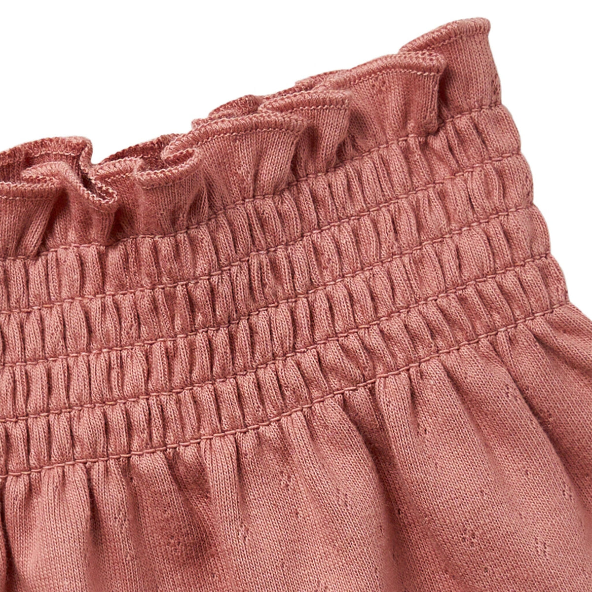Close-up of a pink textured fabric with ruffled top edge on a white background